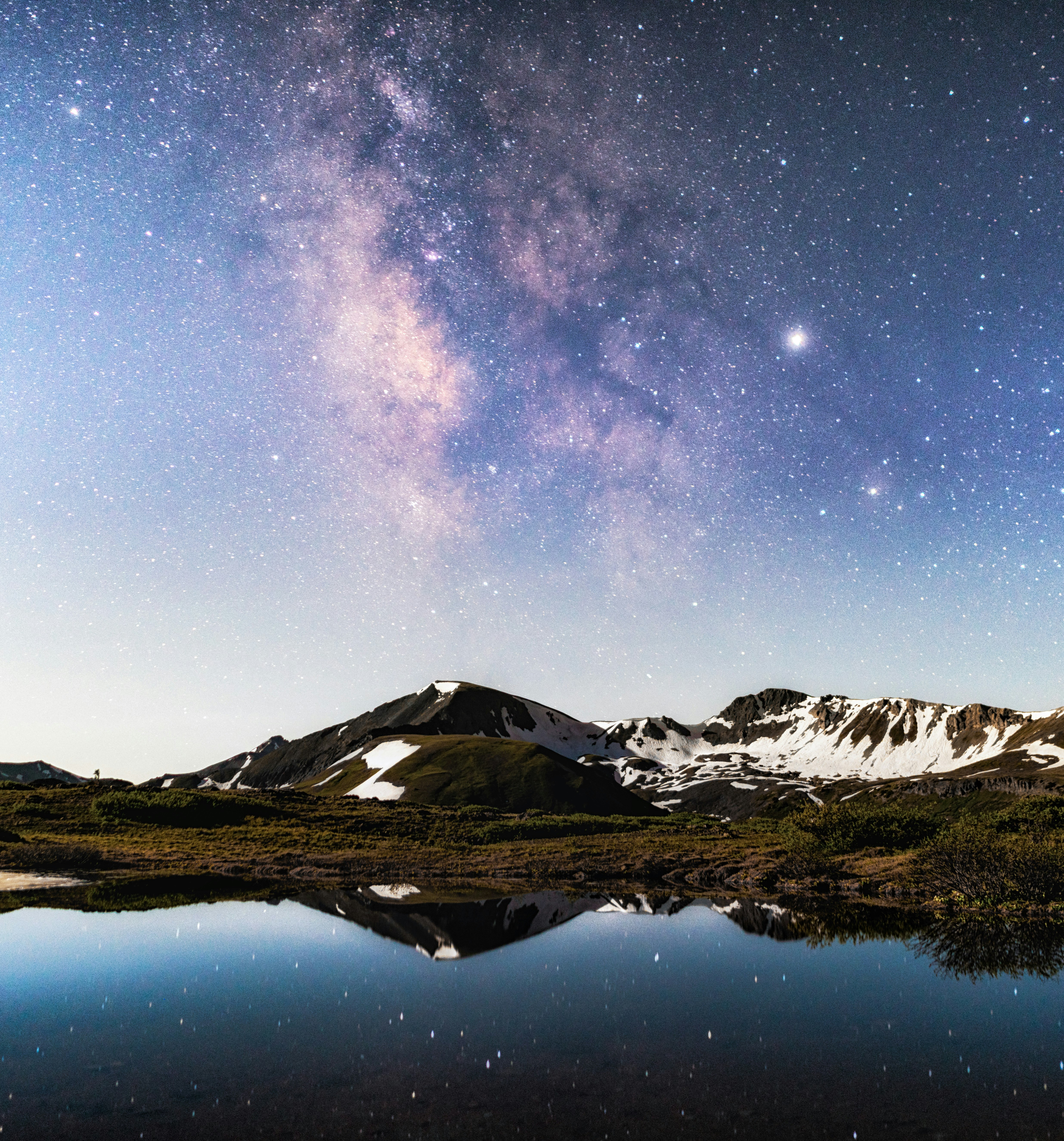 snow covered mountain near lake under starry night